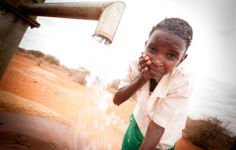 Niño limpiándose con el agua de una fuente